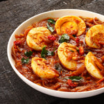 Spicy and flavorful Egg Curry with boiled eggs simmered in a rich tomato and onion gravy, garnished with fresh herbs and dried red chilies.